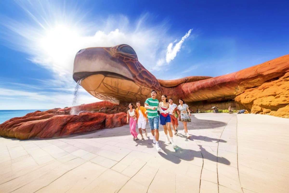 VinWonders Grand Park Ho Chi Minh Family group running past large dinosaur sculpture at VinWonders Grand Park Ho Chi Minh theme park with ocean view