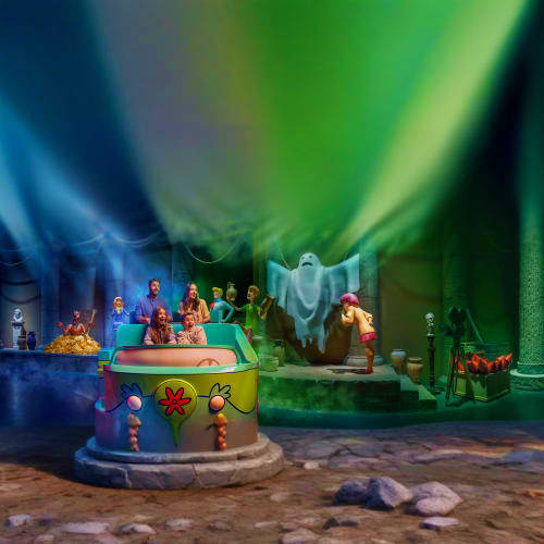 Colorful themed attraction scene at Warner Bros World Abu Dhabi with costumed characters, glowing green and blue atmospheric 