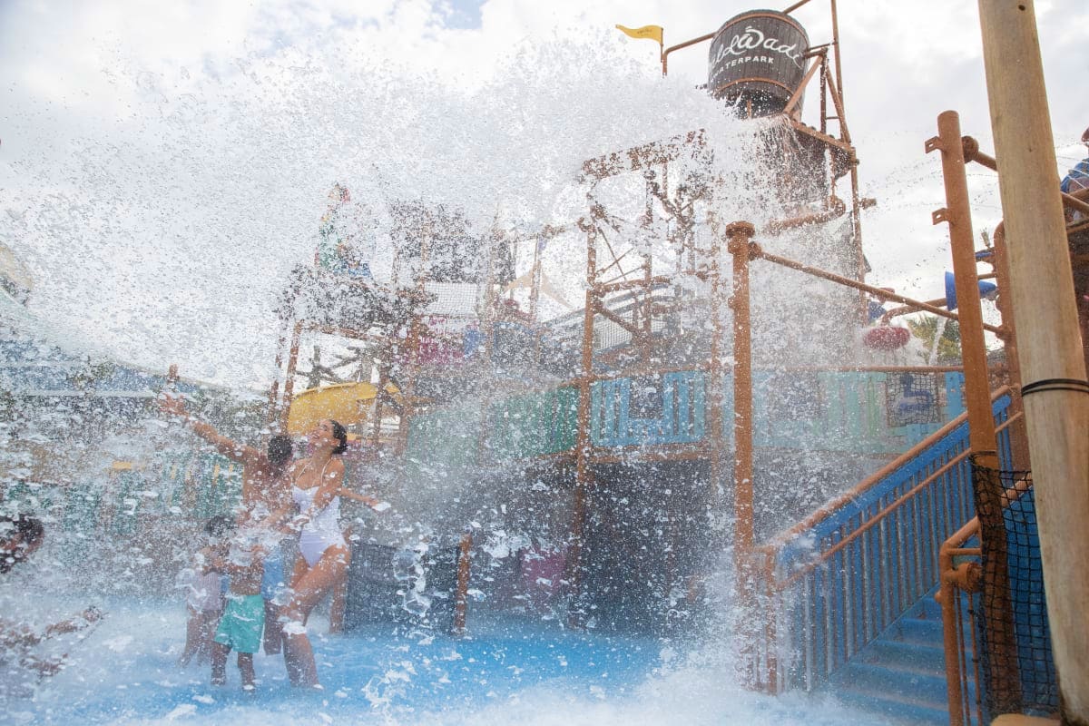 Wild Wadi Water Park Children playing in massive water spray at Wild Wadi Water Park with rusty metal structures and water tower in background
