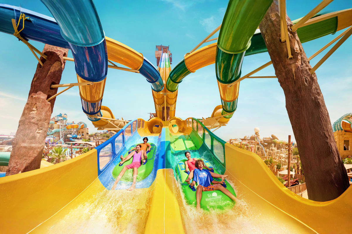 Yas Waterworld Families sliding down yellow and green water slides with colorful tube slides overhead at Yas Waterworld theme park