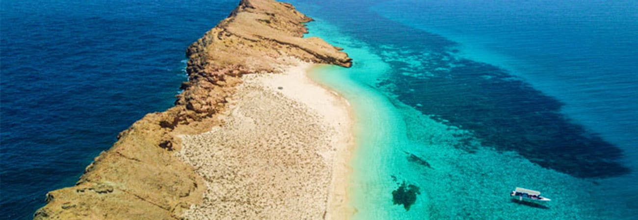 Aerial view of Damaniyat Island's white sand beach with turquoise waters and rocky coastline