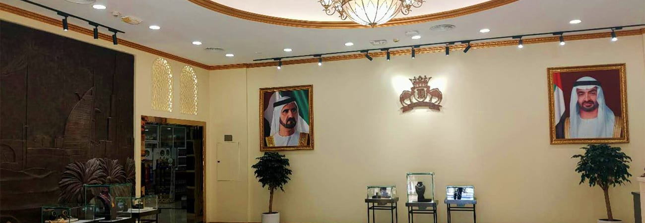 Elegant interior of UAE palace or government building with portrait paintings, decorative crown emblem, and display cases