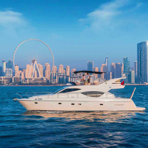 Luxury white motor yacht anchored in Dubai waters with the Ferris wheel and skyline in background