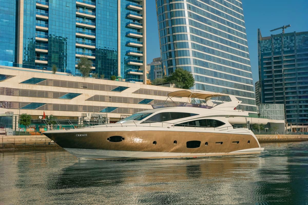 Luxury motor yacht Gold X43 moored in urban waterway with modern high-rise buildings in background