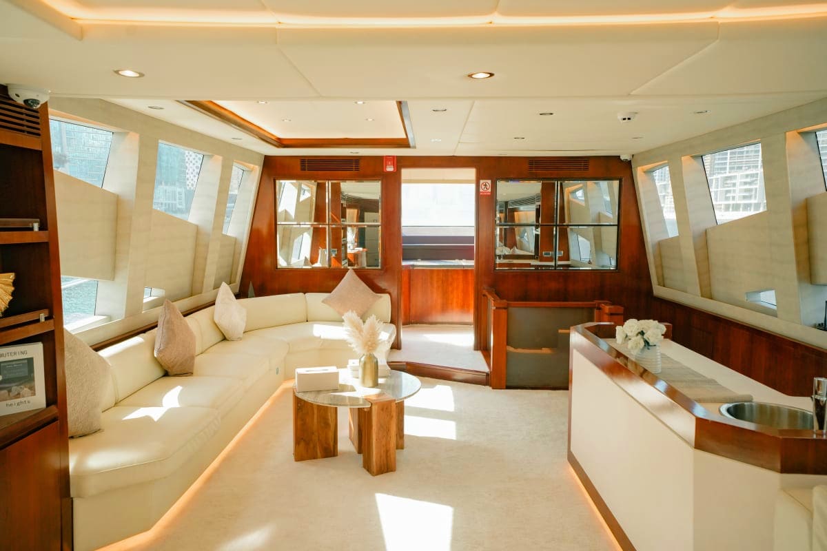 Gold X43 luxury yacht interior with cream seating, wooden finishes, and panoramic windows overlooking city skyline
