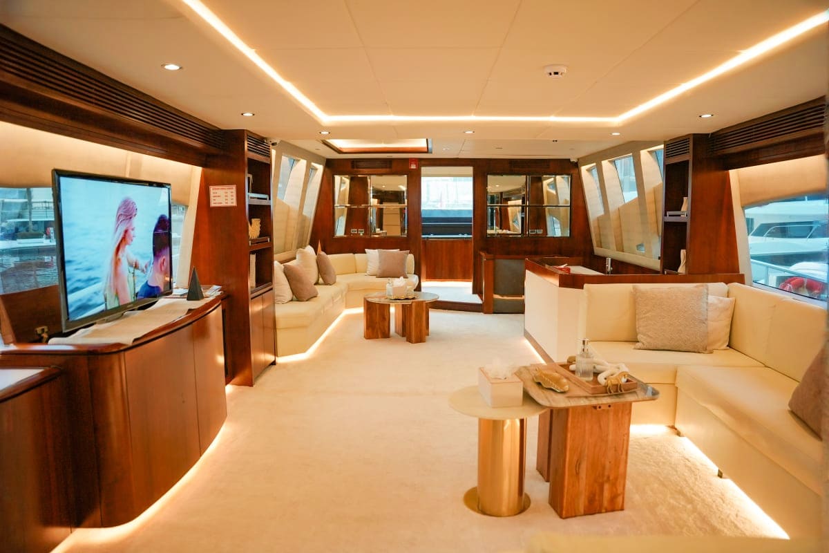 Luxurious yacht interior with cream seating, wood cabinetry, flat-screen TV, and ambient ceiling lighting