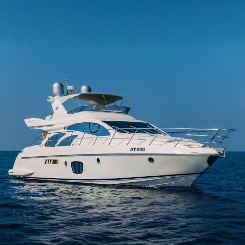 Luxury white motor yacht anchored in clear blue ocean water under cloudless sky
