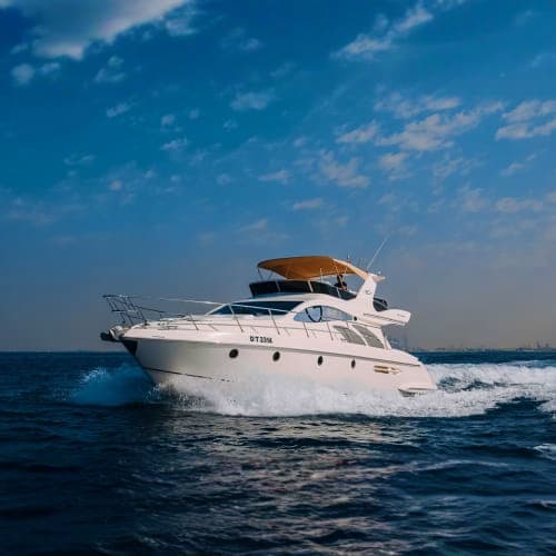 White luxury motor yacht with brown canopy cruising through blue ocean waters under clear sky
