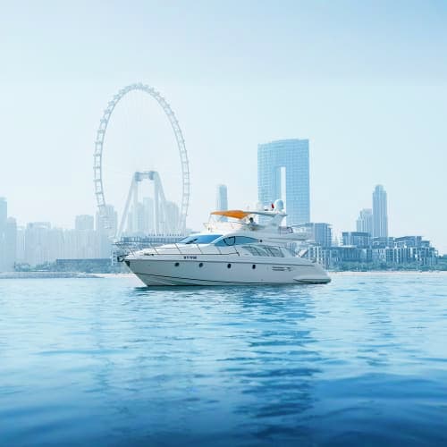 Luxury yacht anchored in Dubai waters with Ferris wheel and city skyline in background