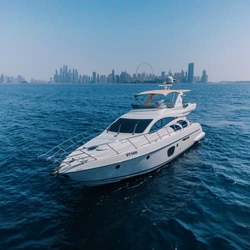 Luxury white motor yacht anchored in blue water with Dubai skyline in background