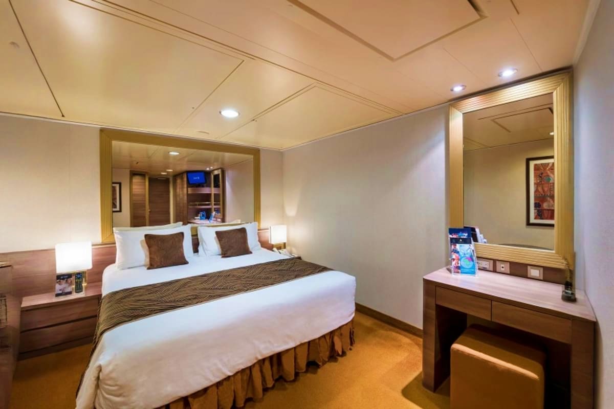 MSC Seaview South America Voyage Luxury cruise ship stateroom with queen bed, en-suite bathroom, vanity desk, and modern wood and cream furnishings