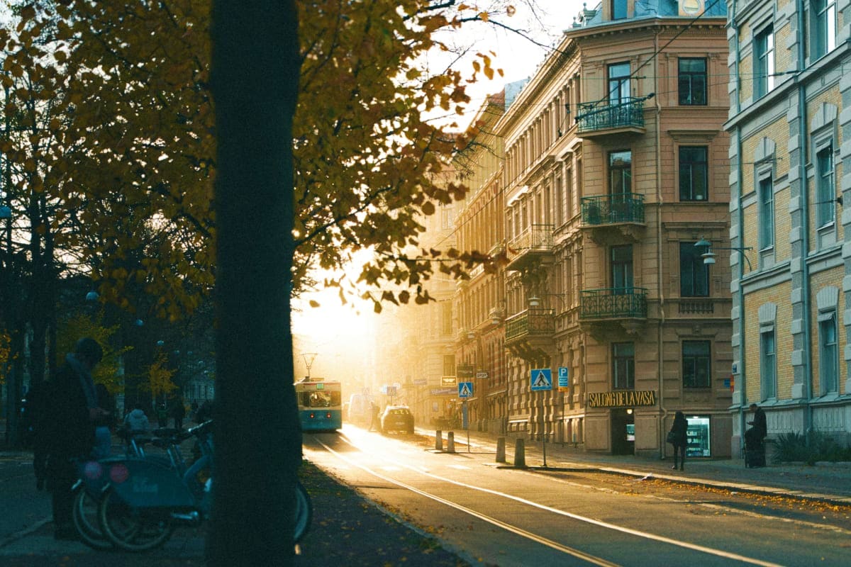 Historic European city street in Riga with autumn foliage, classical buildings, vintage tram, and golden sunlight illuminatin