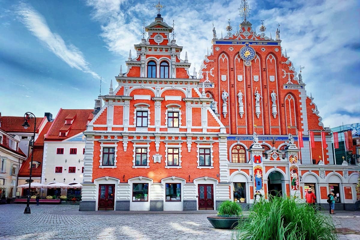 Historic red brick building with white stone trim and ornate spires in Old Town Riga, Latvia, featuring traditional architect