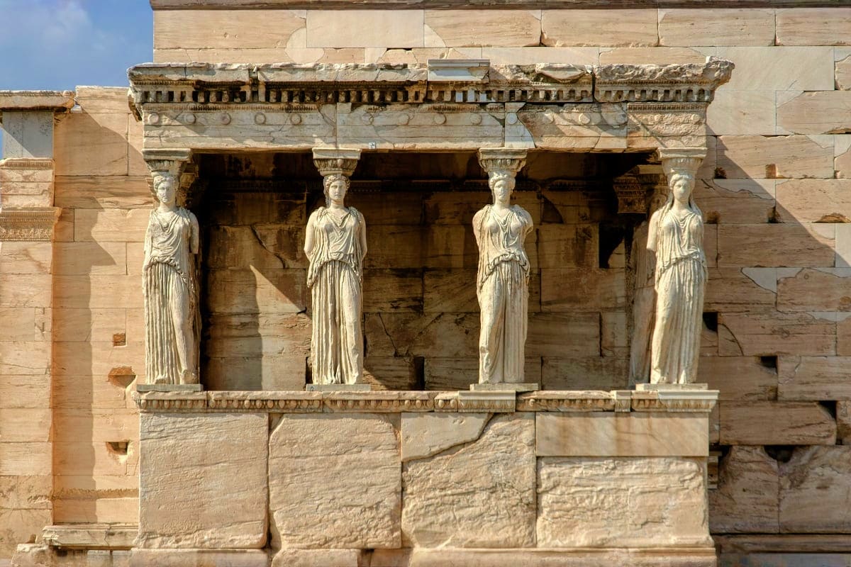 Ancient Greek temple facade with four carved female figures as columns supporting ornate stone entablature and roof structure