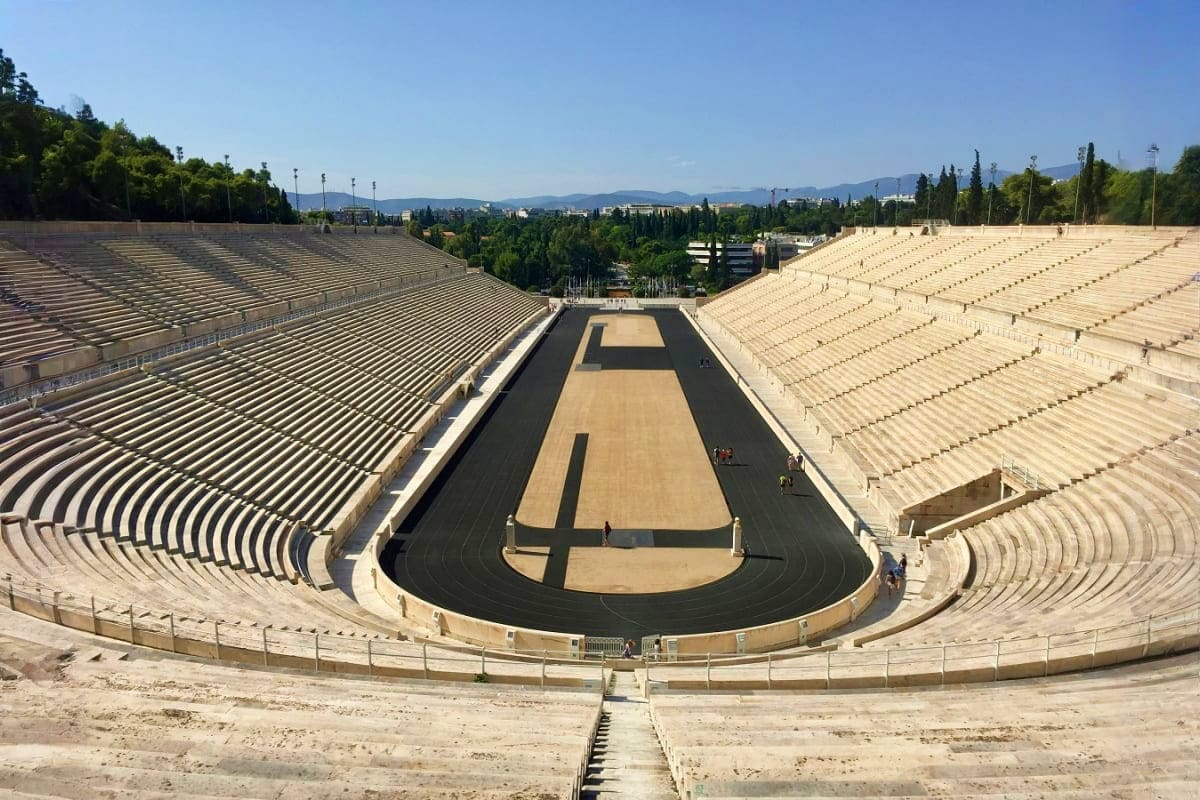 Panathenaic Stadium in Athens with its iconic oval track, tiered marble seating, and mountain views in the background