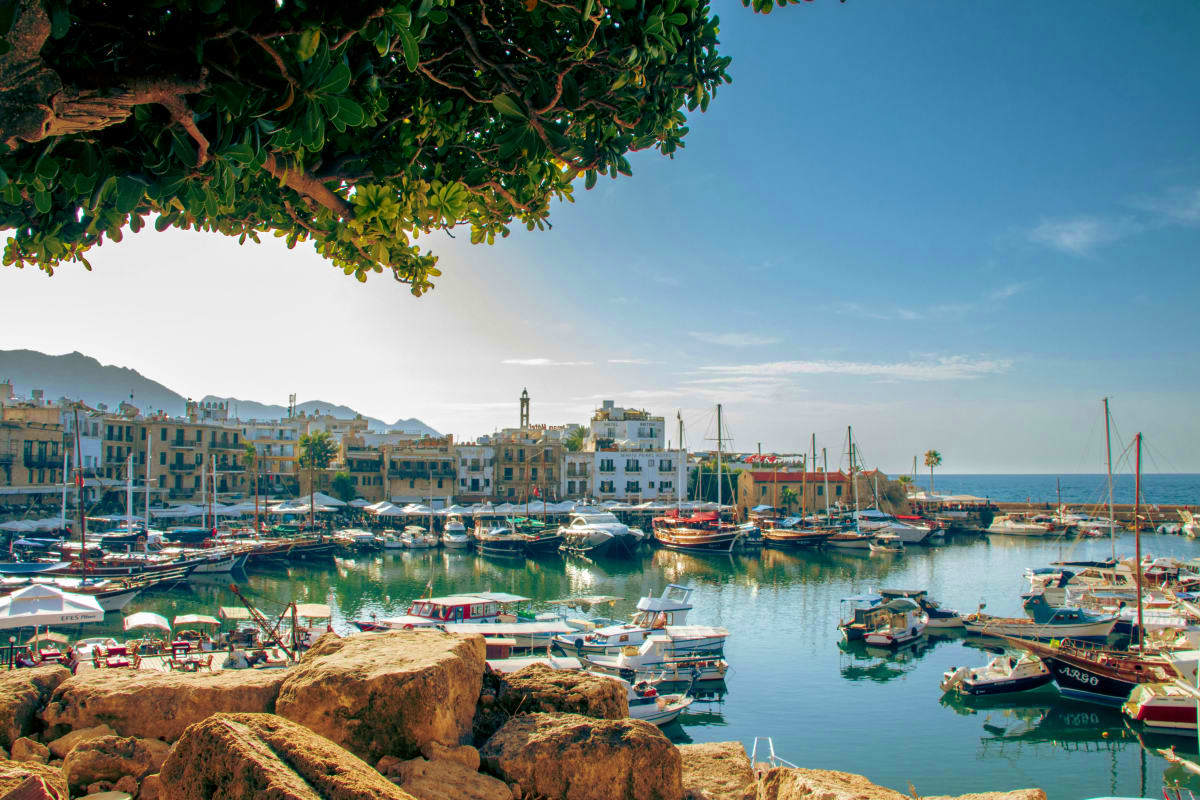 Picturesque Mediterranean harbor in Cyprus with colorful fishing boats, historic waterfront buildings, and rocky coastline un