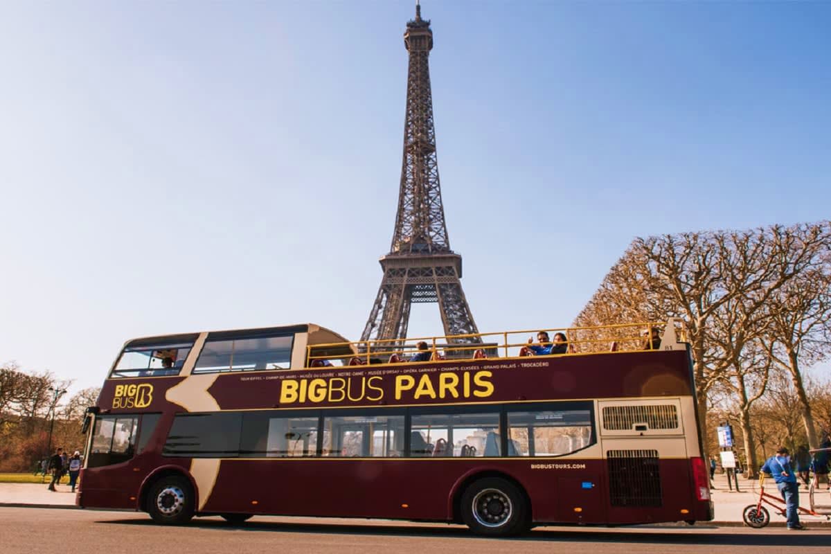 Double-decker Big Bus Paris tour bus with passengers on upper deck in front of Eiffel Tower