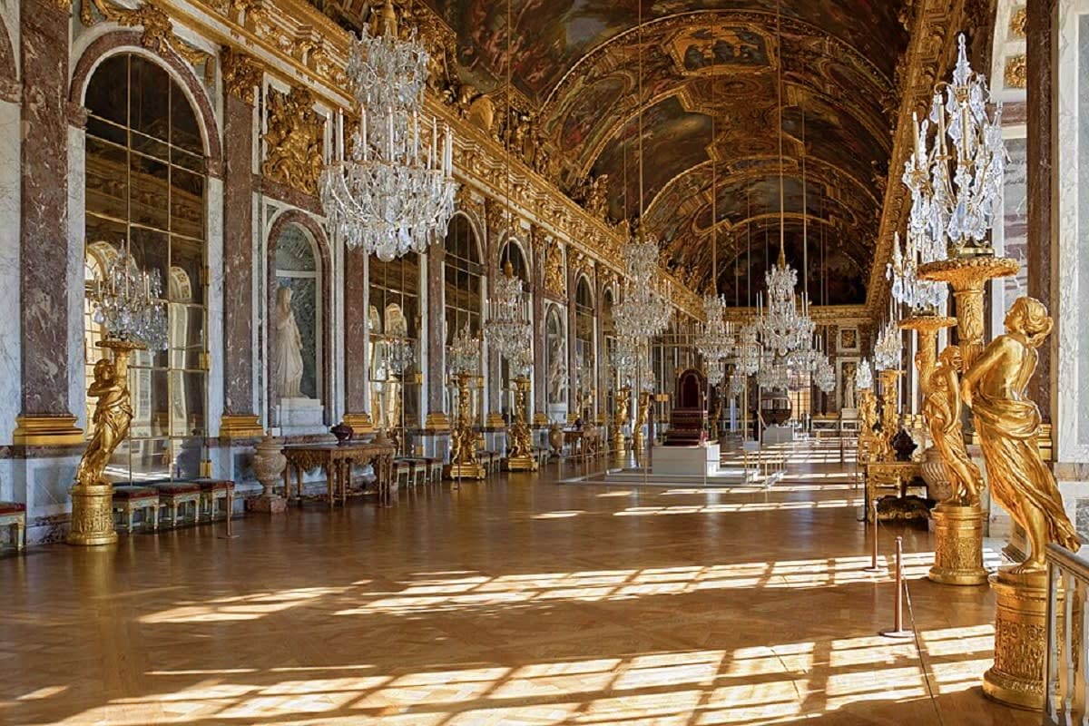 Hall of Mirrors at Palace of Versailles with ornate gold decorations, crystal chandeliers, and arched ceiling