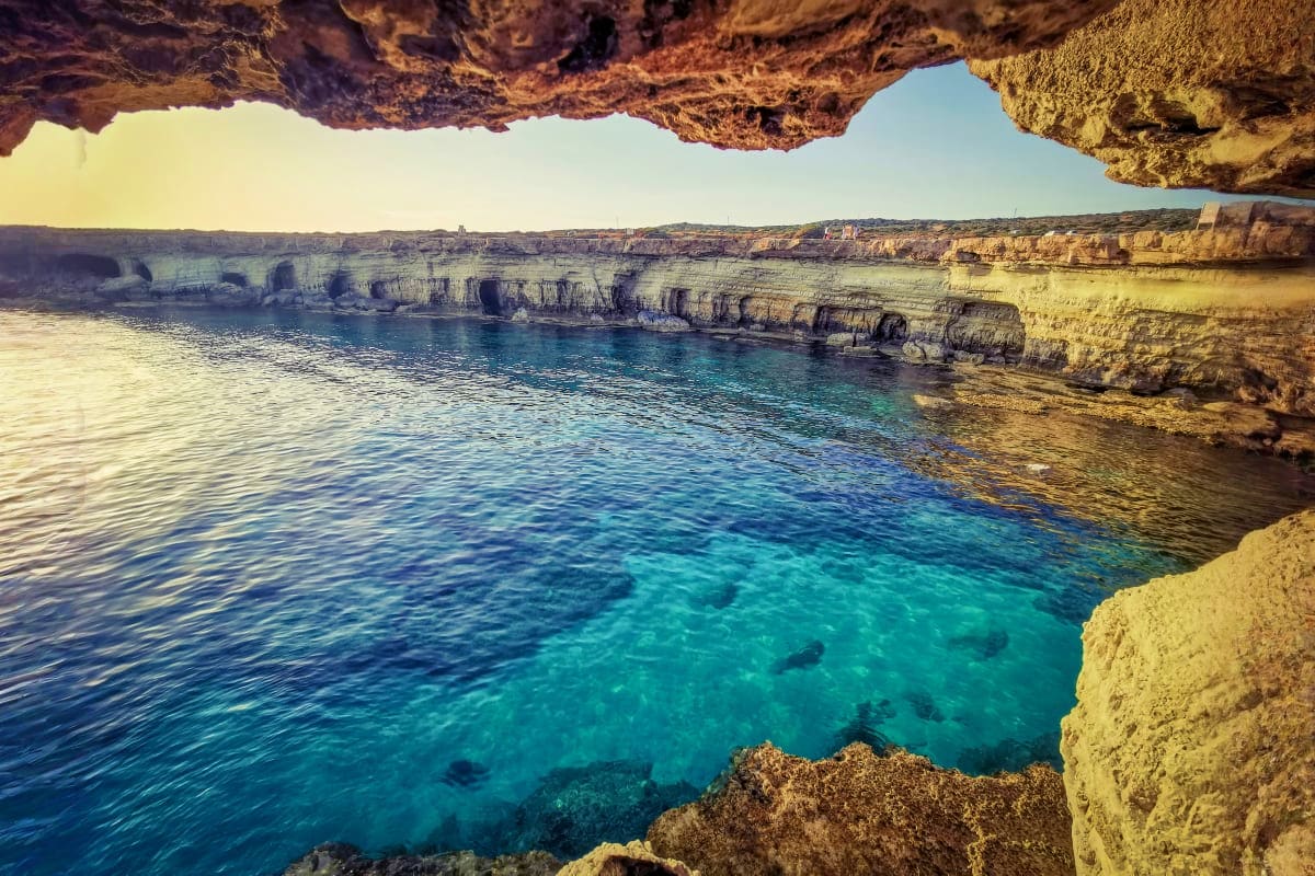 View through natural rock arch of turquoise Mediterranean sea and limestone cliffs on Cyprus coastline