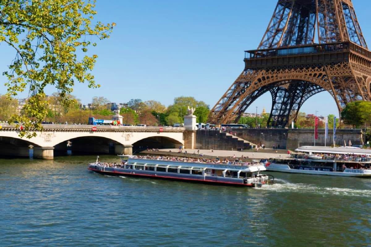 River cruise boat on the Seine beneath the Eiffel Tower and Bir-Hakeim bridge in Paris on a sunny day