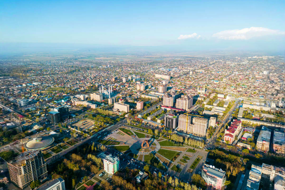 Aerial view of Bishkek city with modern buildings, parks, and sprawling urban landscape under clear sky