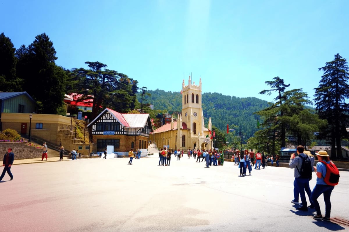 Christ Church in Shimla's main plaza with tourists and colonial architecture surrounded by pine forests under clear blue sky