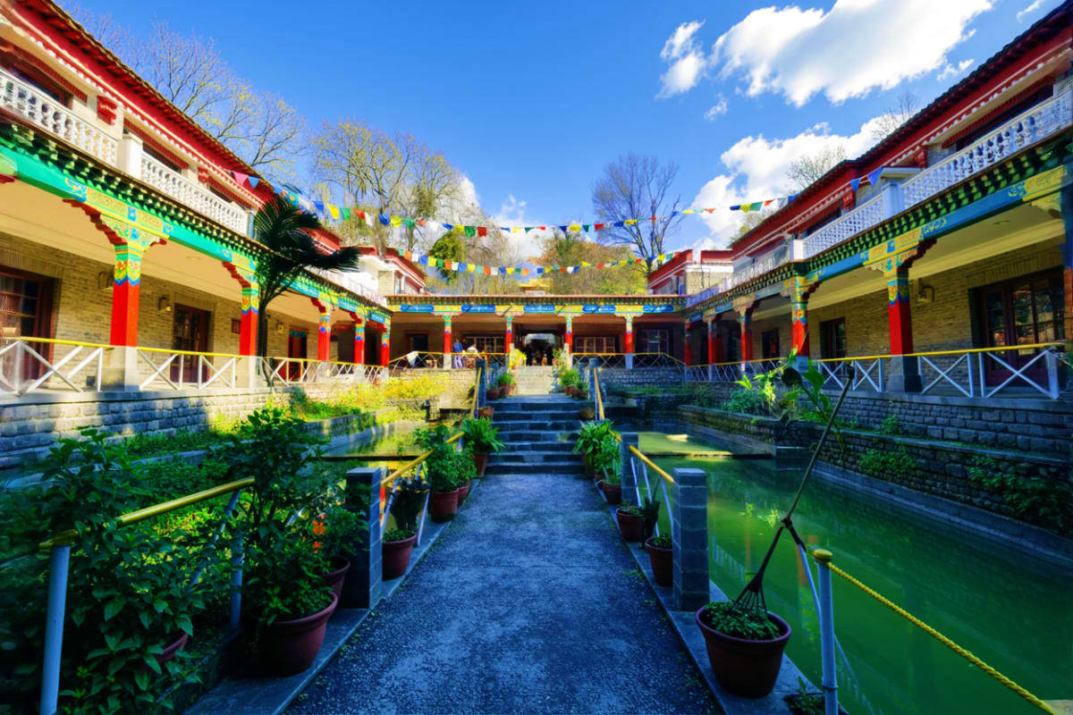 Colorful Tibetan Buddhist monastery courtyard with red pillars, prayer flags, and traditional architecture in Himachal Prades