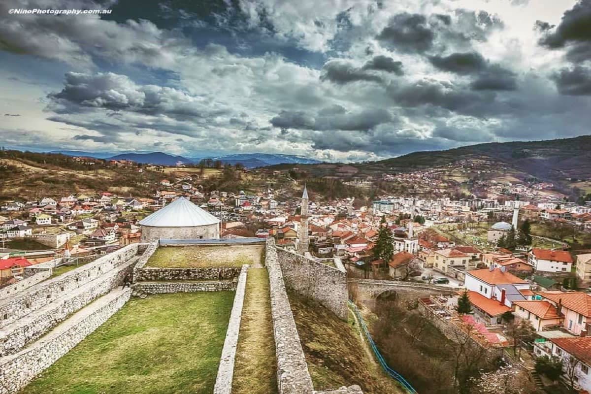 Explore Bosnia & Herzegovina Aerial view of Travnik fortress with white domed structure overlooking historic town nestled in Bosnian valley with mountains