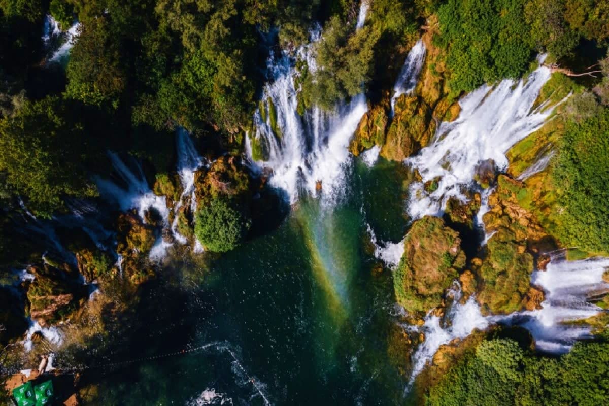 Explore Bosnia & Herzegovina Aerial view of cascading waterfalls surrounded by lush green forest and moss-covered rocks in Bosnia and Herzegovina
