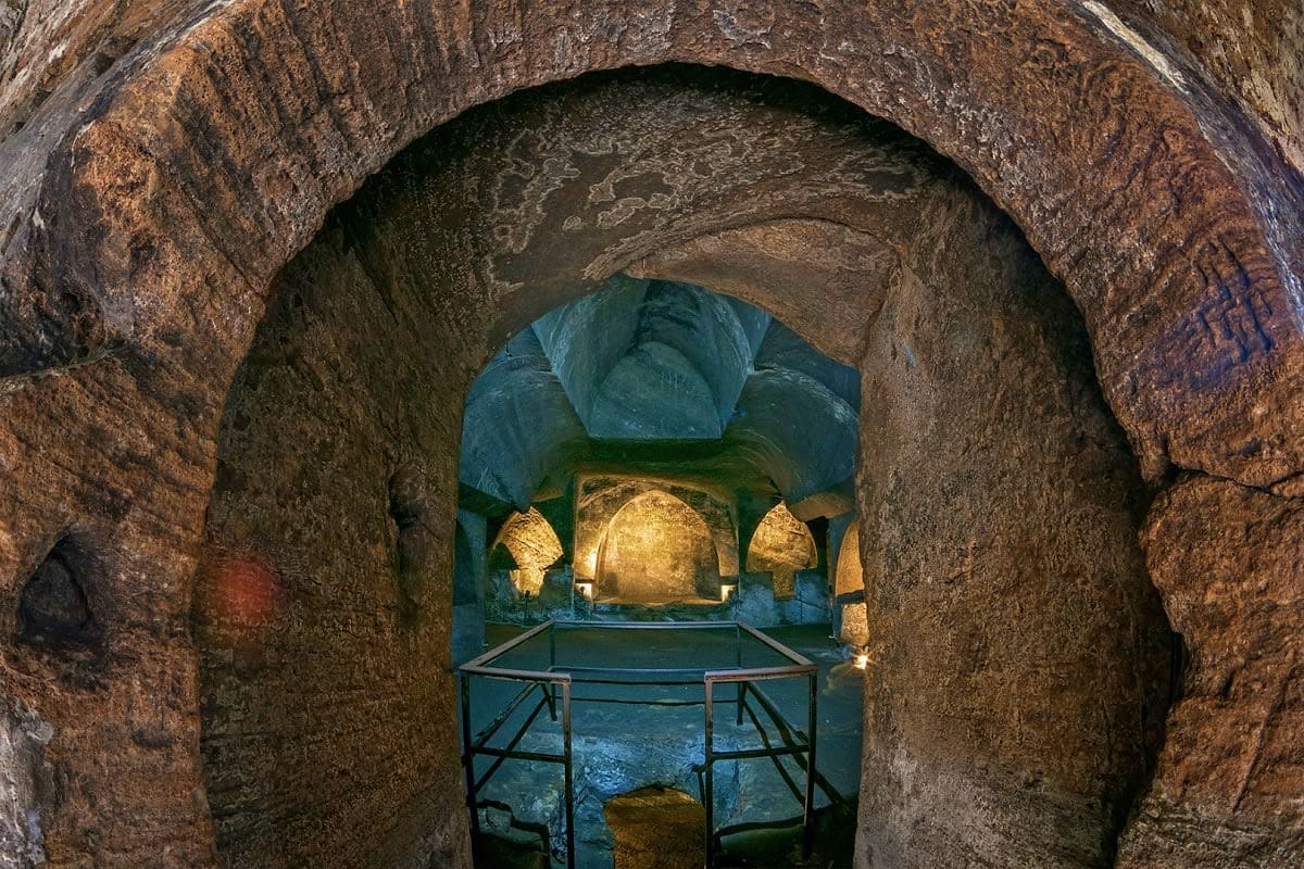 Explore Bosnia & Herzegovina Ancient stone archway framing illuminated Buddhist statue in cave temple, Bosnia and Herzegovina archaeological site