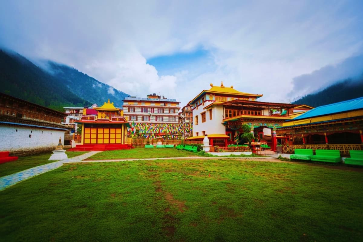 Manali Kasol Holiday Package with Adventure Nature and Hot Springs Colorful traditional Tibetan Buddhist monastery with golden roofs and ornate decorations nestled in a green valley surrounded