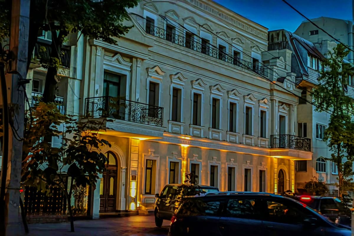 Historic white neoclassical building with ornate facade and wrought-iron balconies illuminated at dusk in Moldova