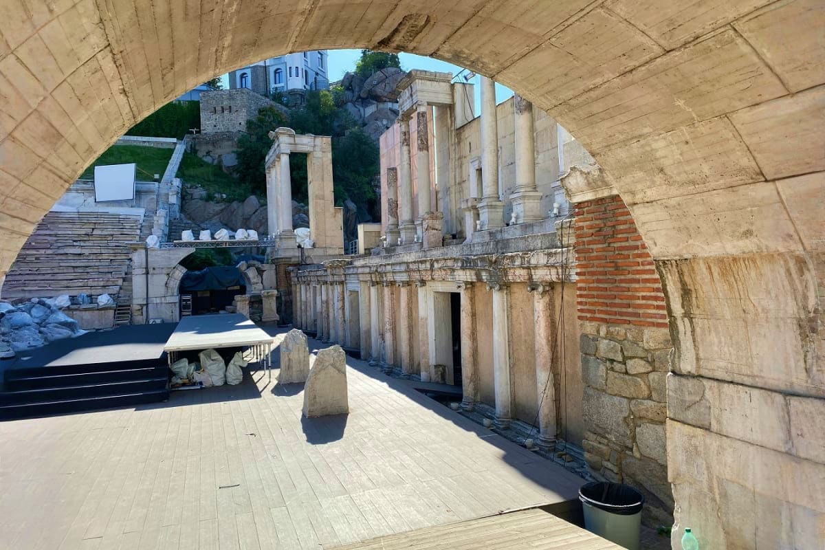 View through concrete archway of ancient Roman theater ruins with stone columns and weathered brick structures in Bulgaria