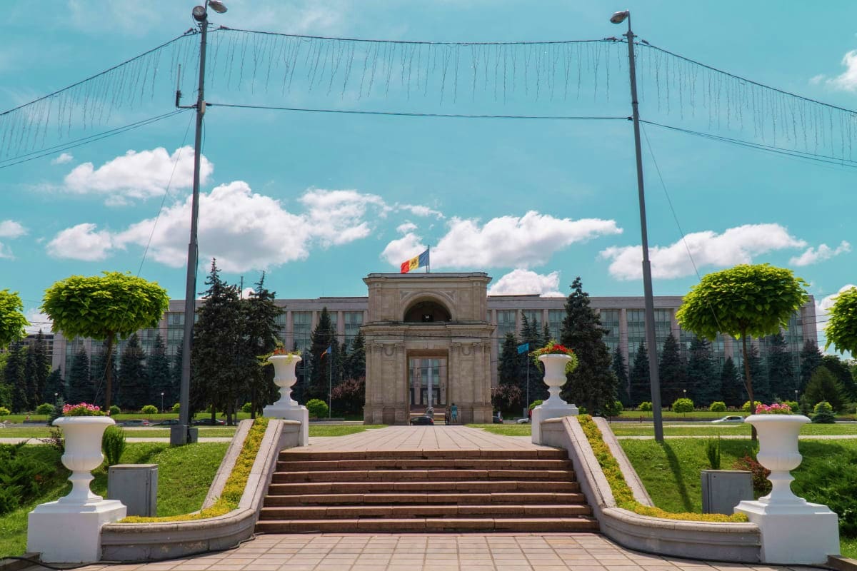 Symmetrical staircase approach to Parliament Palace in Chisinau, Moldova with ornamental urns and manicured gardens under blu