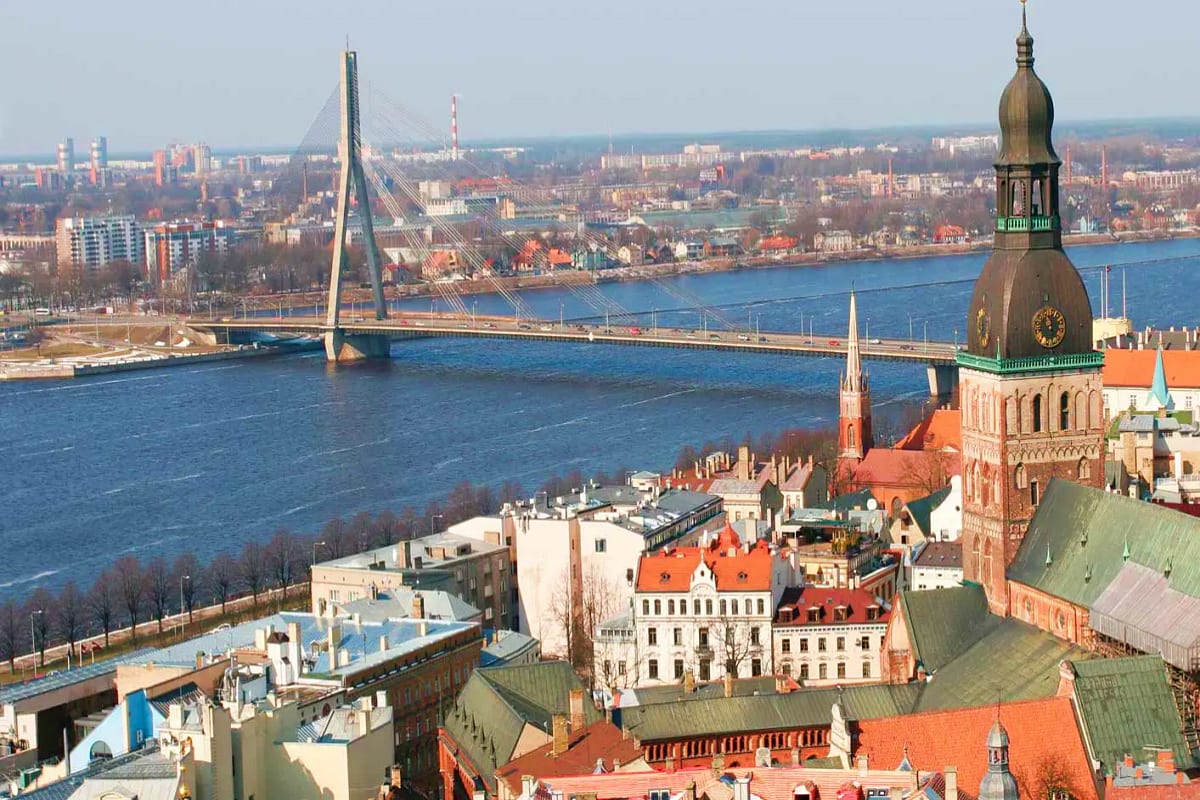 Baltic Capitals Discovery Tour Aerial view of Riga's Old Town with Daugava River, cable-stayed bridge, and historic church spire overlooking cityscape