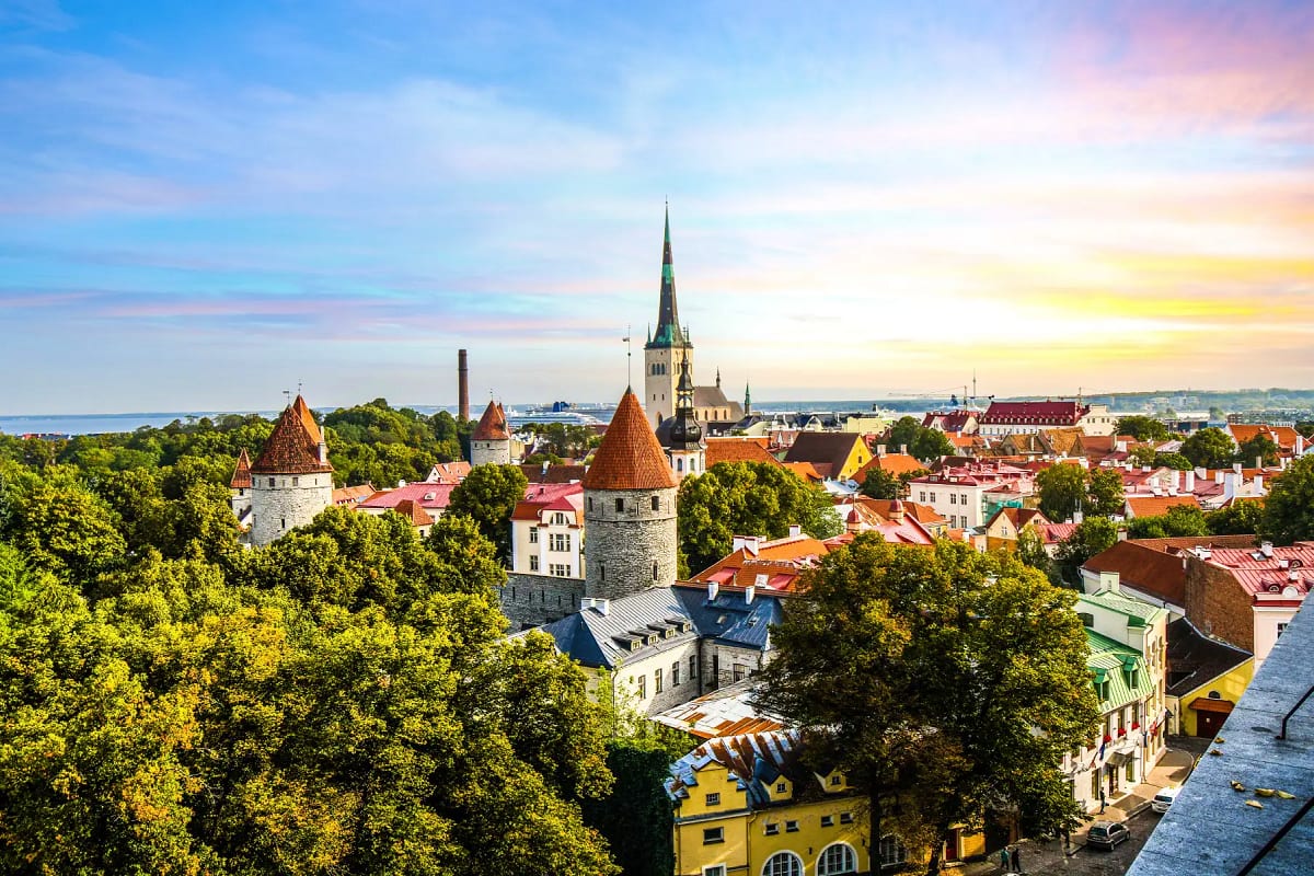 Tallinn Old Town skyline at sunset with medieval towers, colorful buildings, and church spire overlooking the Baltic Sea coas