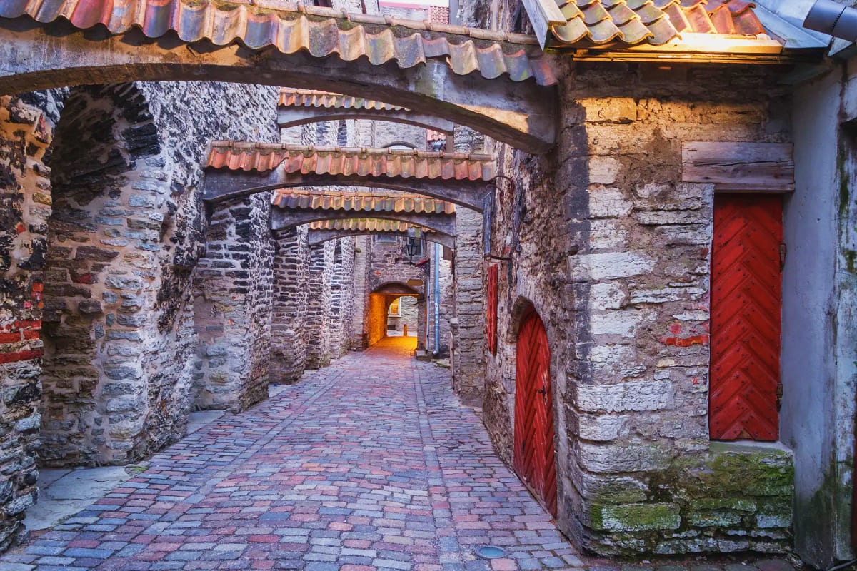 Medieval stone passageway with red wooden doors and barrel-vault ceiling in historic Old Town district
