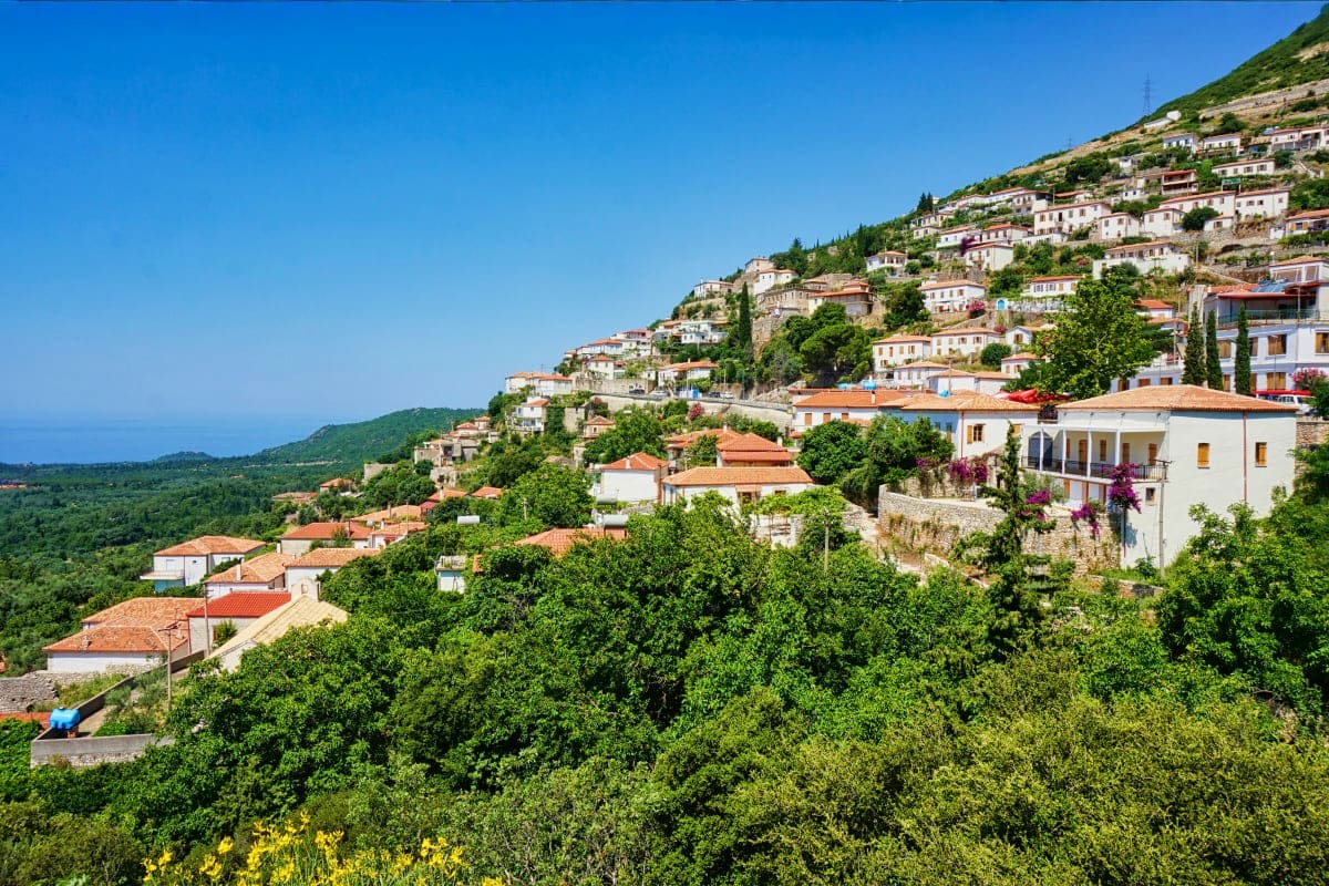 Hillside village in Albania with white and terracotta buildings nestled among green vegetation overlooking coastal landscape