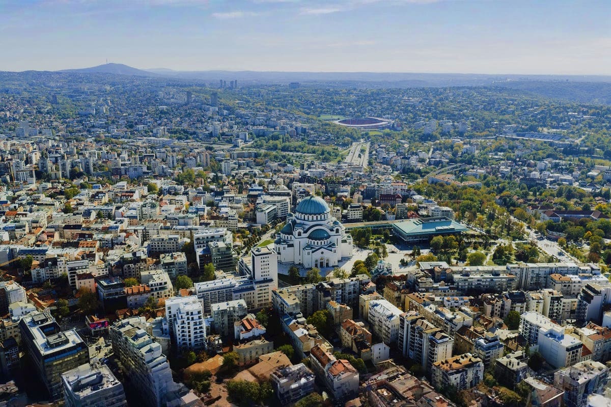 Aerial view of Belgrade with Church of Saint Sava dome, urban cityscape, and mountains in distance