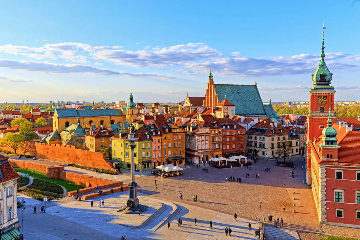 Warsaw Old Town skyline with colorful historic buildings, castle square, and green-domed tower under blue sky