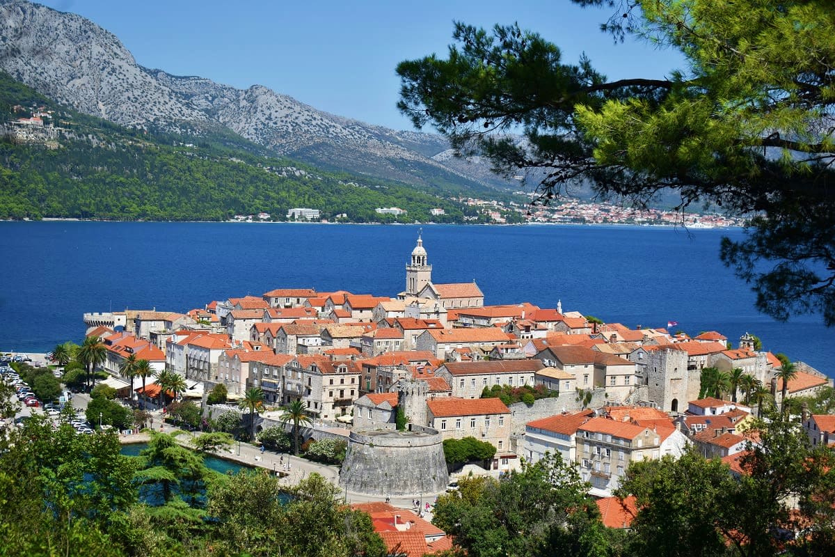 Aerial view of Dubrovnik's Old Town walled peninsula with red-roofed buildings, cathedral, and Adriatic Sea surrounded by mou
