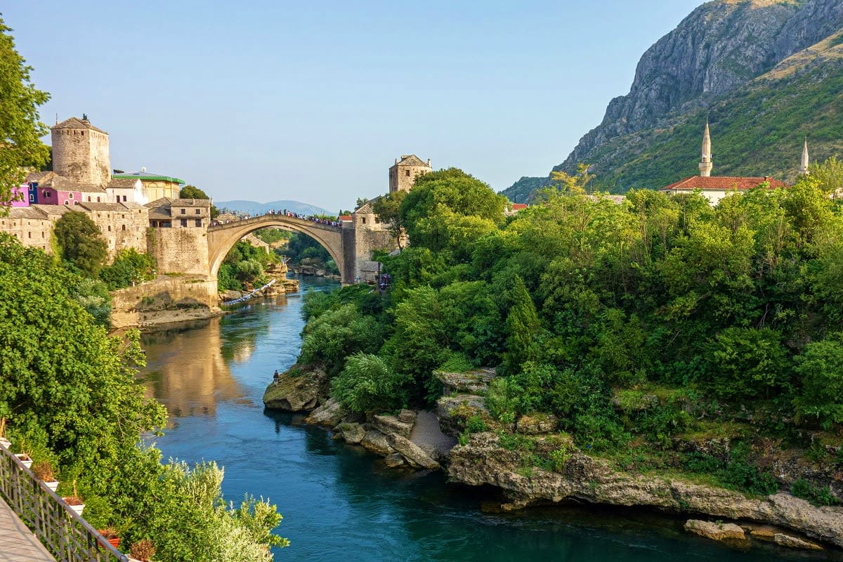 Stari Most stone arch bridge spanning turquoise river with historic tower and mosque minarets in Mostar, Bosnia and Herzegovi