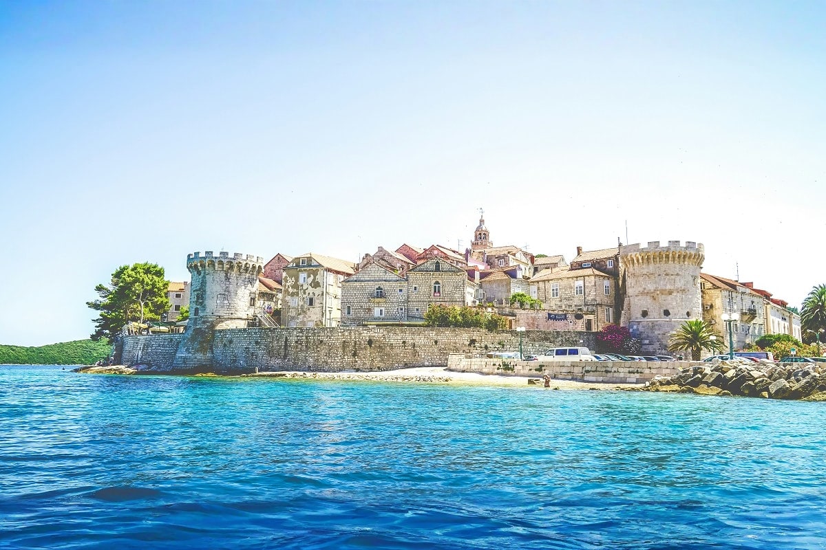 Medieval walled town of Dubrovnik with stone fortifications and historic buildings viewed from turquoise Adriatic Sea waters