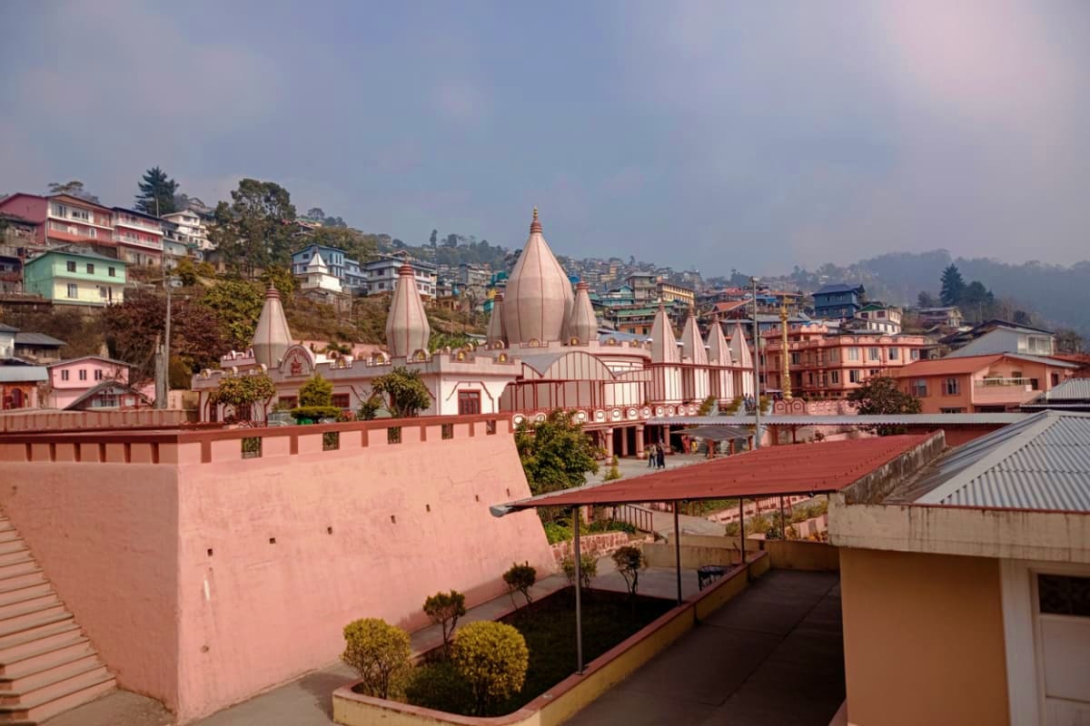 Hindu temple with distinctive spires overlooking a hillside town nestled in misty Himalayan mountains