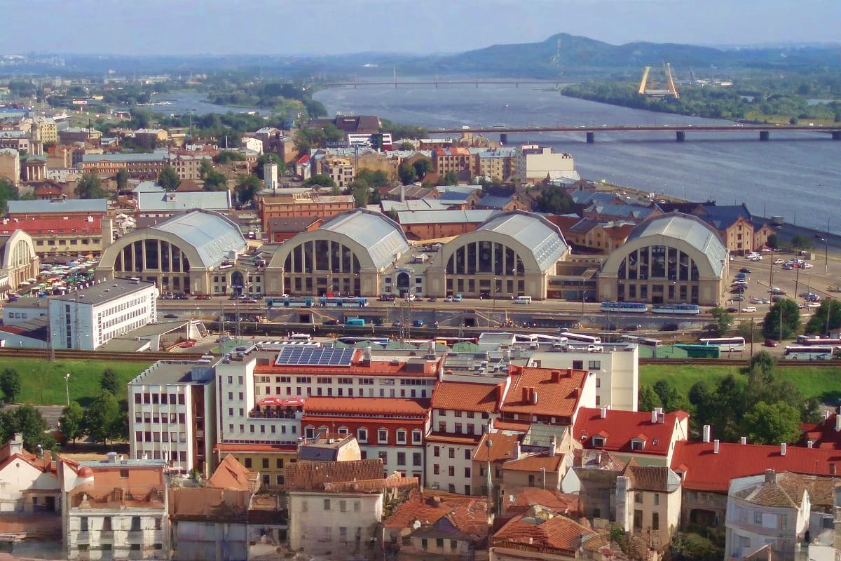 Aerial view of Riga's central railway station with distinctive arched domes, Daugava River, and bridges in the background