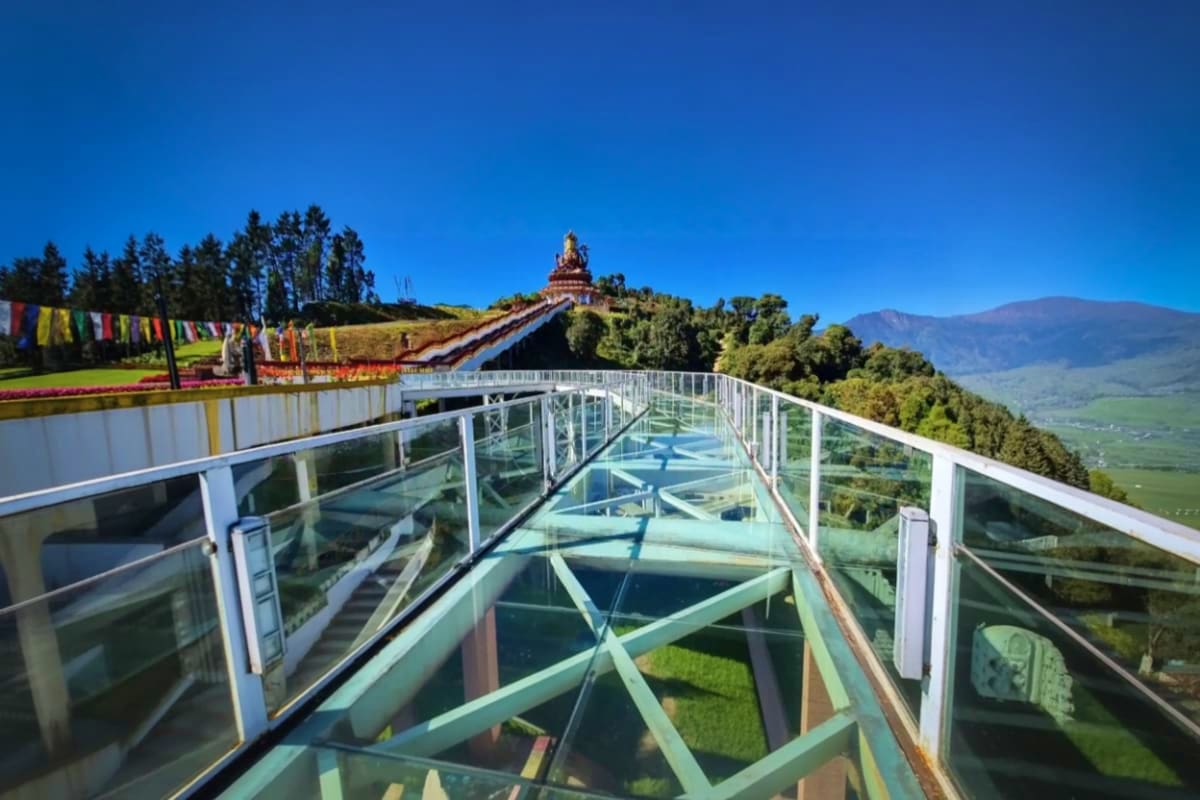 Glass skywalk with mountain valley views and Buddhist temple on hilltop in Sikkim, India