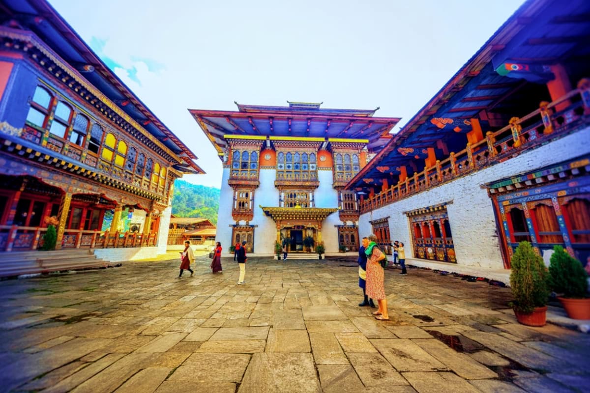 Trongsa Dzong courtyard in Bhutan with ornate wooden buildings, colorful traditional architecture, and visitors walking on st