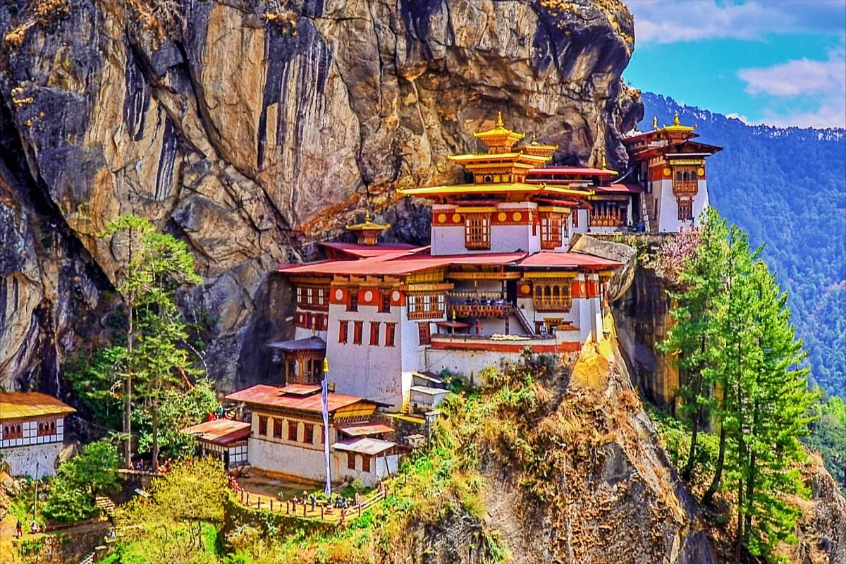 Tiger's Nest Monastery perched on a cliff face in Paro, Bhutan, with golden spires, traditional architecture, and forested mo