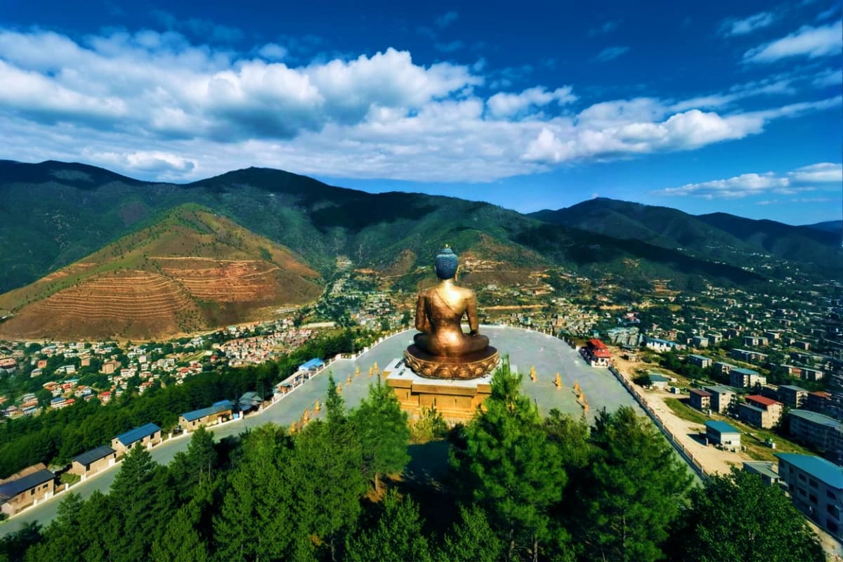 Giant golden Buddha statue overlooking Thimphu valley with mountains and buildings in Bhutan