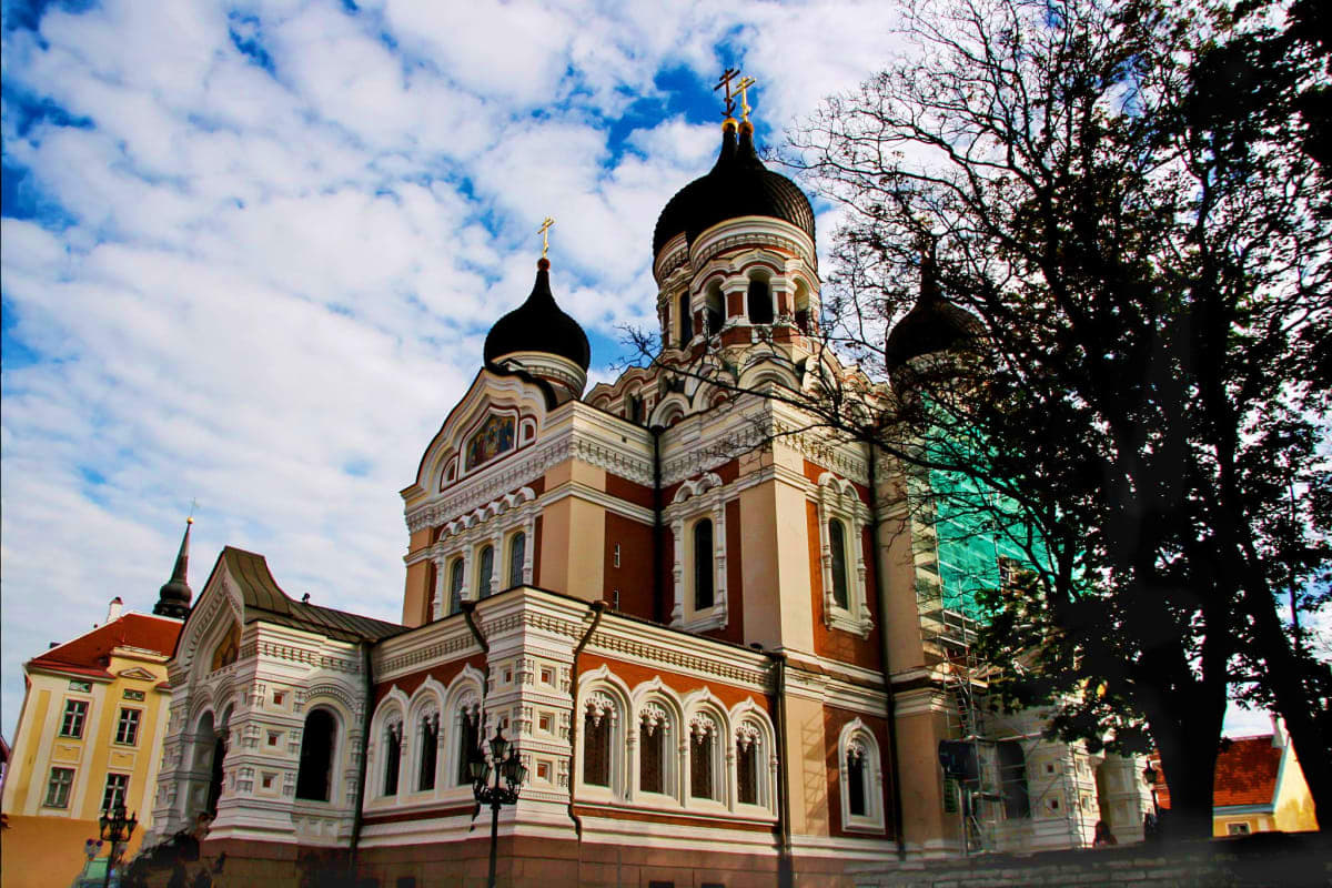 Alexander Nevsky Cathedral in Tallinn, Estonia with distinctive black domes and ornate cream and orange facade on a sunny day
